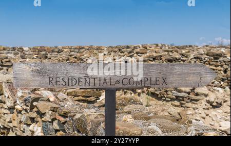 Cartello complesso residenziale: Lettere dipinte di nero, Freccia di legno contro le rocce e cielo blu. Foto Stock