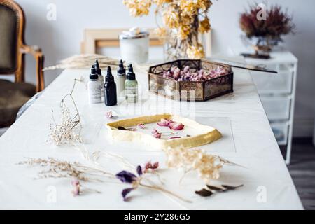 Preparazione di fiori secchi su un tavolo con stampo in resina e pigmenti. Decorazioni naturali, arte floreale, decorazioni per la casa fai da te, artigianato sostenibile, interni Foto Stock