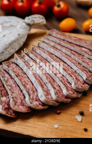 Primo piano di salame salato a fette a bordo, ideale per piatti gourmet e presentazioni di salumi Foto Stock