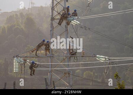 YICHANG, CINA - 9 SETTEMBRE 2024 - i dipendenti dell'energia elettrica lavorano su una torre d'acciaio vicino alla ferrovia di Shuigang nel villaggio di Xikouping, città di Yichang, cent Foto Stock