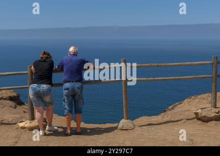 Uomo e donna appoggiati su una ringhiera di legno che guarda fuori dalla scogliera dell'Oceano Atlantico a Cabo da Roca, parco nazionale, Portogallo, Europa. Foto Stock