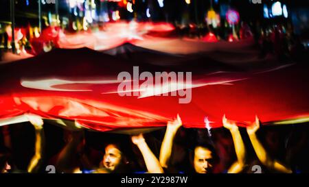 Izmir, Turchia. 9 settembre 2024. L'anniversario della liberazione di Smirne del 9 settembre, una data importante nella guerra d'indipendenza turca. Nell'evento in cui è stato celebrato il 102° anniversario della liberazione di Izmir dall'occupazione nemica, una gigantesca bandiera turca di 350 metri è stata portata dalle persone che partecipano alla processione delle fiaccolate. Crediti: İdil Toffolo/Alamy Live News Foto Stock