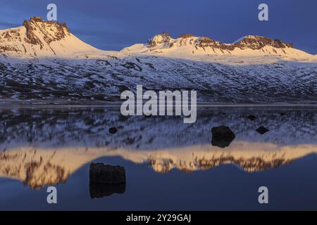 Montagne innevate riflesse in un fiordo alla luce della sera, Berufjoerdur, fiordi orientali, Islanda, Europa Foto Stock