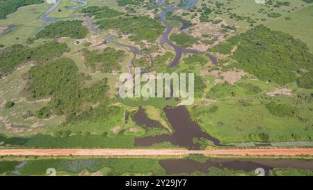 Veduta aerea della strada sterrata di Transpantaneira che attraversa una laguna su un piccolo ponte nel tipico paesaggio delle paludi Pantanal del Nord, Mato Grosso, Brazi Foto Stock