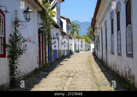 Ammira la montagna attraverso una tipica strada acciottolata con edifici coloniali nel tardo pomeriggio, nella storica città di Paraty, Brasile, Sud America Foto Stock