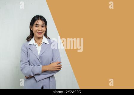 profilo di una donna lavoratrice in piedi sorridente e sicura di sé, la donna indossa una lunga camicia viola chiaro, accanto alla spa negativa vuota Foto Stock