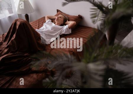 Donna anziana che si allunga a letto, si sta divertendo, si risveglia Foto Stock