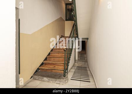 Ingresso ad una vecchia casa con scale in legno e ringhiera in ferro battuto in metallo verniciato Foto Stock