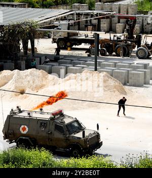 Jenin, Cisgiordania, Palestina. 9 aprile 2022. Un palestinese lancia un cocktail molotov su un veicolo dell'esercito israeliano nel campo profughi di Jenin, durante un raid israeliano su larga scala nel campo della Cisgiordania settentrionale. Durante il raid, si sono verificati gravi scontri tra palestinesi e truppe israeliane durante i quali il palestinese Ahmad al-Saadi, 23 anni, è stato ucciso con un colpo d'arma da fuoco mentre altri tredici palestinesi hanno subito ferite da proiettile. Il raid segue l'uccisione di soldati israeliani venerdì di Raad Hazem, 28 anni, presumibilmente dietro un attacco mortale a Tel Aviv, giovedì sera. Secondo fonti locali durante il Foto Stock