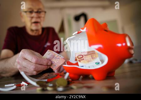 Berlino, Germania. 5 settembre 2024. Foto simbolica sul tema delle finanze nella vecchiaia - povertà nella vecchiaia. Un vecchio si siede a casa al tavolo di fronte a un salvadanaio rotto e conta i soldi. Berlino, 5 settembre 2024. Credito: dpa/Alamy Live News Foto Stock