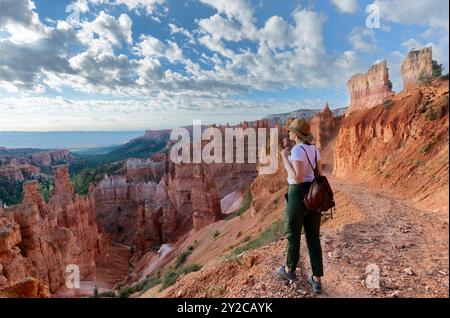 Ragazza che si rilassa durante una vacanza a piedi. Donna in piedi accanto all'hoodoo Thor's Hammer sulla cima della montagna che guarda una splendida vista. Bryce Canyon National Foto Stock