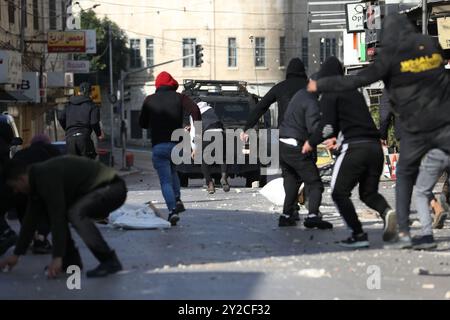 Nablus, Cisgiordania, Palestina. 30 dicembre 2022. I palestinesi si scontrano con le forze israeliane a Nablus durante un raid israeliano nella città della Cisgiordania. Le forze israeliane hanno effettuato il raid per arrestare un membro del gruppo militante palestinese della Lions' Den. I giovani palestinesi hanno reagito all'incursione lanciando pietre contro veicoli corazzati israeliani Foto Stock