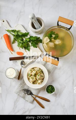 Composizione con gnocchi di carne cotti in brodo vegetale su piano di marmo Foto Stock