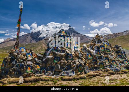 Piramide di bandiere di preghiera di fronte alle montagne innevate dell'Himalaya al passo di Lalung la, 5050 m di altitudine sulla Friendship Highway tra Lhasa Foto Stock