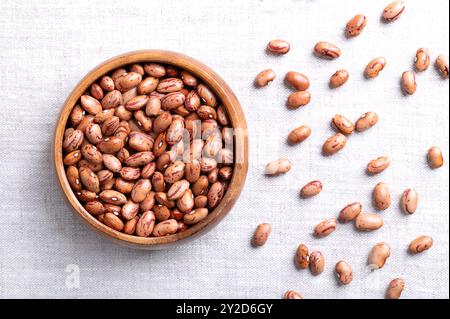 Fagioli di mirtilli rossi, fagioli Borlotti in ciotola di legno su lino. Color marrone chiaro striato con varietà rossa del fagiolo comune Phaseolus vulgaris. Foto Stock