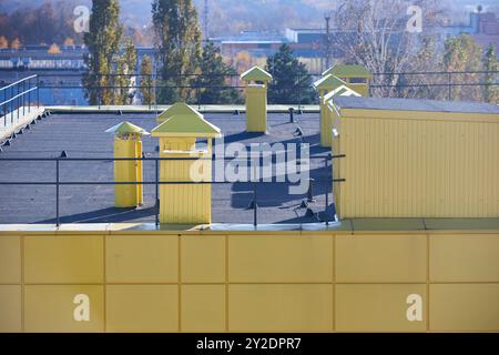 Sistema di ventilazione per lo scarico del tetto dell'aria di grandi edifici commerciali industriali. Camini con cappuccio, canne fumarie e condotti in fila sul tetto, messa a fuoco selettiva Foto Stock