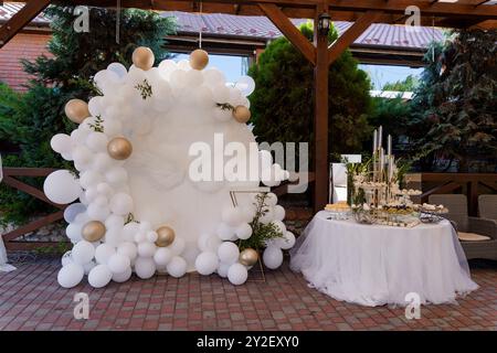 Elegante allestimento per feste all'aperto con decorazioni in mongolfiera bianche e dorate e tavolo da dessert. Foto Stock