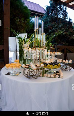 Elegante display da tavolo per dessert all'aperto con candele e dolcetti. Foto Stock