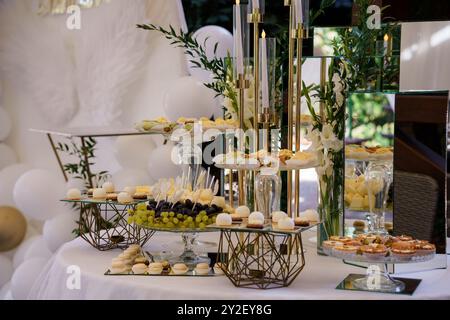 Elegante tavolo da dessert con sofisticato arredamento in oro e delicati pasticcini per un ambiente di lusso. Foto Stock