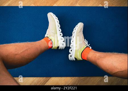 BERNA, SVIZZERA, 10 SETTEMBRE 2024: Su Running Super Shoes Cloudflow 4 sulle gambe di Runner professionista. La cosiddetta scarpa illegale. Sfondo blu Foto Stock