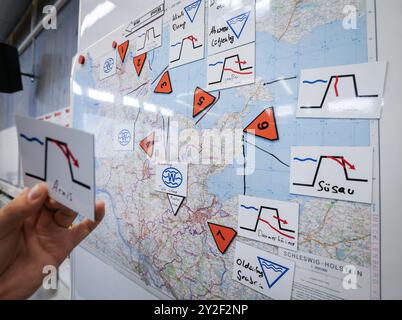 Kiel, Germania. 10 settembre 2024. Un vigile del fuoco si trova su una mappa generale dello Schleswig-Holstein nell'area operativa durante un evento stampa durante l'esercizio di pianificazione per la squadra di crisi per lo scenario "maremoto baltico". Con un'operazione di pianificazione, gli operatori di soccorso in caso di catastrofi si preparano fino a giovedì a Kiel per essere dispiegati in caso di forte ondata di tempesta nel Mar Baltico come quella di ottobre. Credito: Christian Charisius/dpa/Alamy Live News Foto Stock