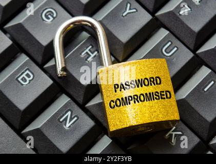 Vista dall'alto del testo password compromessa inciso sul lucchetto con sfondo della tastiera. Concetto di password e sicurezza informatica. Foto Stock