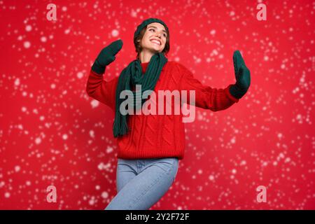 Foto ritratto giovane donna in cerca di copyspace in sciarpa mittens isolato vibrante colore rosso sfondo Foto Stock