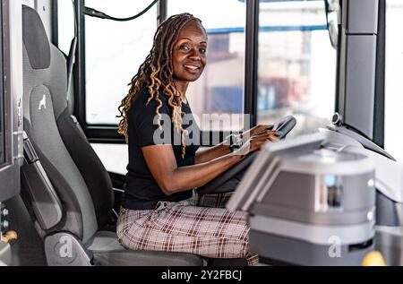 Flensburg, Germania. 10 settembre 2024. L'autista di autobus keniota Millicent Awiti è seduto al volante di un autobus presso il deposito di Flensburg. Il ministro dei trasporti dello Schleswig-Holstein Madsen (CDU) e l'ambasciatore keniota Mokaya Orina hanno dato il benvenuto ai cinque futuri conducenti di autobus del Kenya. Lavoreranno quindi per "Aktiv Bus Flensburg". Credito: Axel Heimken/dpa/Alamy Live News Foto Stock