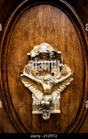 Il battente della porta dal design intricato presenta un angelo grazioso con ali allungate, invitando i visitatori a un pezzo di eleganza parigina immersa nel suo Foto Stock