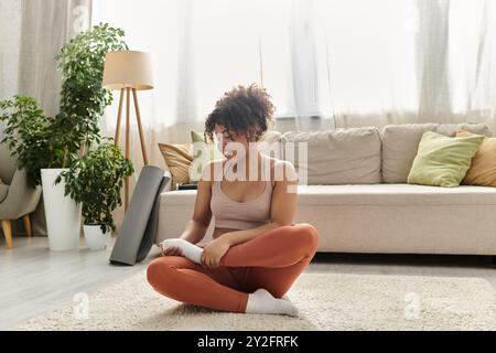 Una giovane donna si rilassa sul pavimento, sorridendo mentre si allunga a casa. Foto Stock