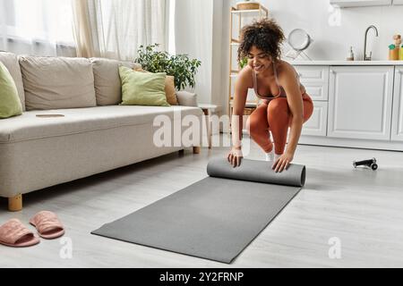 Si prepara a praticare yoga nel suo accogliente salotto pieno di luce naturale. Foto Stock