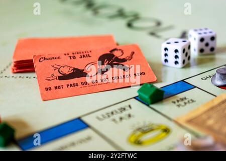 Un momento in Monopoli: Vai direttamente alla carta chance della prigione su un tabellone di gioco Monopoli con marcatori e dadi. Foto Stock