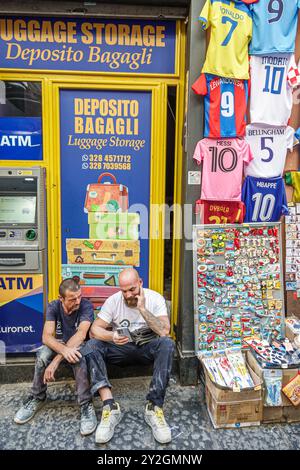 Napoli Italia, via dei tribunali, 2 amici di due uomini, lettura, cellulare, sportello Bancomat, servizio deposito bagagli, Italia Europa europea europea, visita Foto Stock