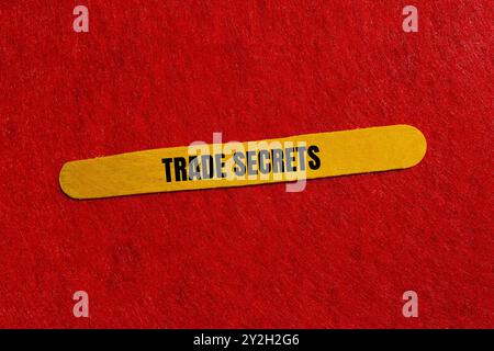 Messaggio segreto commerciale scritto su bastoncino di legno giallo con sfondo rosso. Simbolo dei segreti commerciali concettuali. Copia spazio. Foto Stock