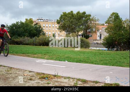 Viladecans, Barcellona-settembre 10.2024: Immagine di un ciclista in movimento su un sentiero circondato da edifici e natura, perfetto per temi urbani e sportivi. Foto Stock