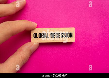 Messaggio di recessione globale scritto su un blocco di legno con sfondo rosa. Simbolo di recessione globale concettuale. Copia spazio. Foto Stock