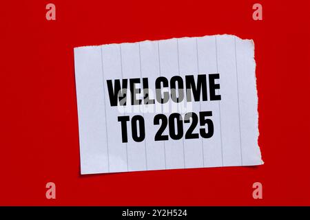 Benvenuto nel messaggio 2025 scritto su un pezzo di carta strappato con sfondo rosso. Benvenuto concettuale nel simbolo 2025. Copia spazio. Foto Stock