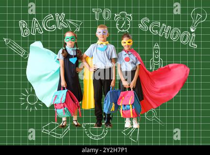 Piccoli studenti in costumi da supereroi su sfondo verde. Torna a scuola Foto Stock