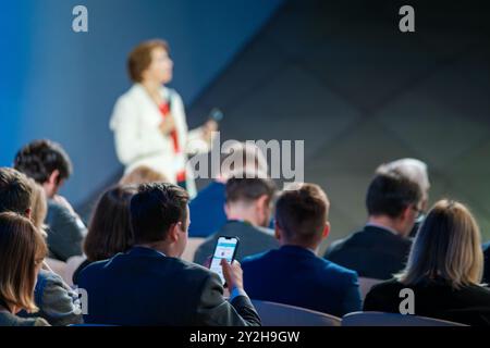 Professionisti che si presentano a una conferenza con i partecipanti che ascoltano e partecipano. Pubblico impegnato e attento in un seminario aziendale. Foto Stock