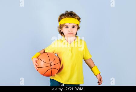 Bambino sportivo in abbigliamento sportivo con palla da basket. Fitness, allenamento e stile di vita attivo per i bambini. Sport per bambini. Giocatore di basket in uniforme sportiva Foto Stock