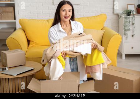 Giovane donna asiatica con nuovi vestiti da pacco a casa Foto Stock