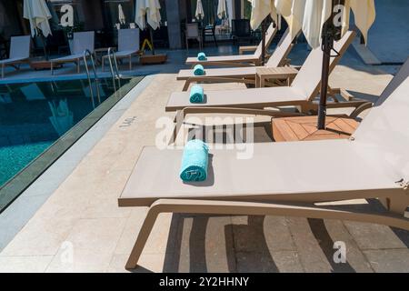 Piscina con lettini, ombrelloni e asciugamani in fila Foto Stock