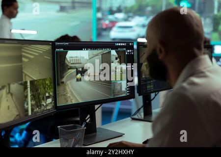 Dipendente che supervisiona il traffico tramite filmati di sorveglianza CCTV in giro per la città, guardando video dal sistema radar ai semafori. Lavorare con telecamere di pubblica sicurezza per la sicurezza stradale. Foto Stock