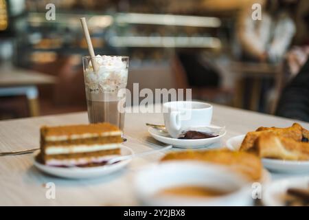 Due tazze di cappuccino con torte e pasticcini su un tavolo di legno. Caffè mattutino nel caffè all'aperto. Foto Stock