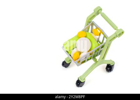 Carrello della spesa in miniatura pieno di varie pillole colorate e vitamine, che rappresentano lo shopping di salute e benessere. Adatto per argomenti relativi al dado Foto Stock