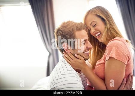 Amore, ridere e abbracciare con la coppia in camera da letto per romanticismo, legame e matrimonio. Luna di miele, vacanza e affitto di case con uomo e donna in vacanza o Foto Stock