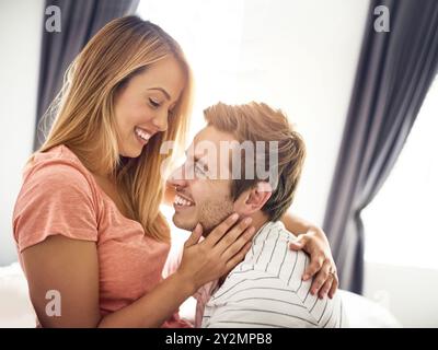 Amore, cura e abbraccio con la coppia in camera da letto per romanticismo, legame e matrimonio. Luna di miele, vacanza e affitto di case con uomo e donna in vacanza o Foto Stock