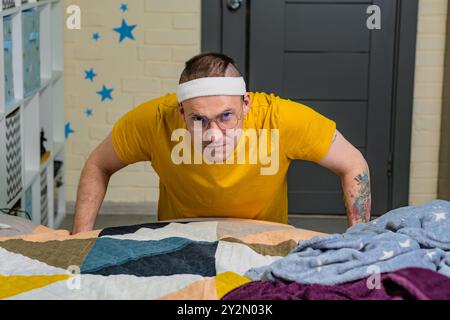 Una persona determinata che fa push-up in una stanza accogliente, focalizzata sull'allenamento fitness mentre indossa un abbigliamento casual. Foto Stock