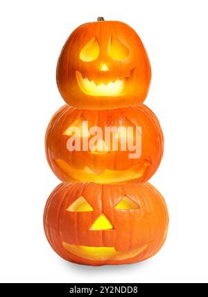 Pila di zucche con volti scolpiti e spettrali su sfondo bianco. Jack-o-Lanterne di Halloween di diverse dimensioni Foto Stock