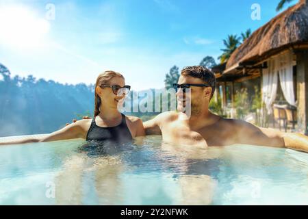 Coppia che si rilassa nella vasca idromassaggio della lussuosa villa nella giungla di Bali. fuga romantica Foto Stock